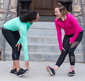 Two women stretching their legs outdoors.