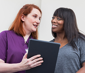 Healthcare provider with digital tablet talking to woman.