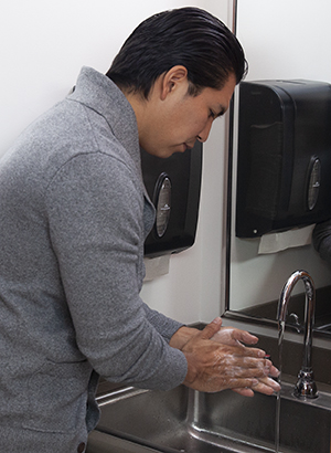 Un hombre lavándose las manos en el lavabo.